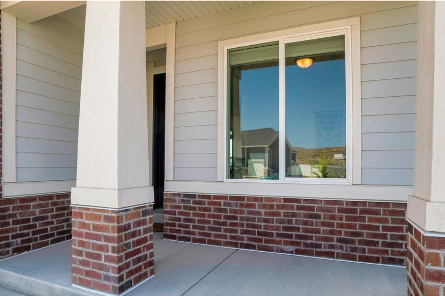 Exterior view of a gliding vinyl window that sits on the front porch of a gray house.