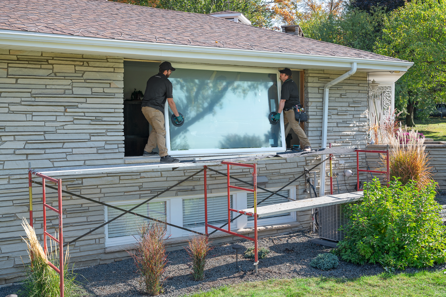 Two Renewal by Andersen installers installing a window in a house. 