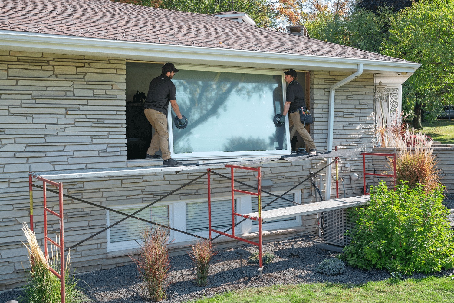 Two Renewal by Andersen installers installing a window in a house.