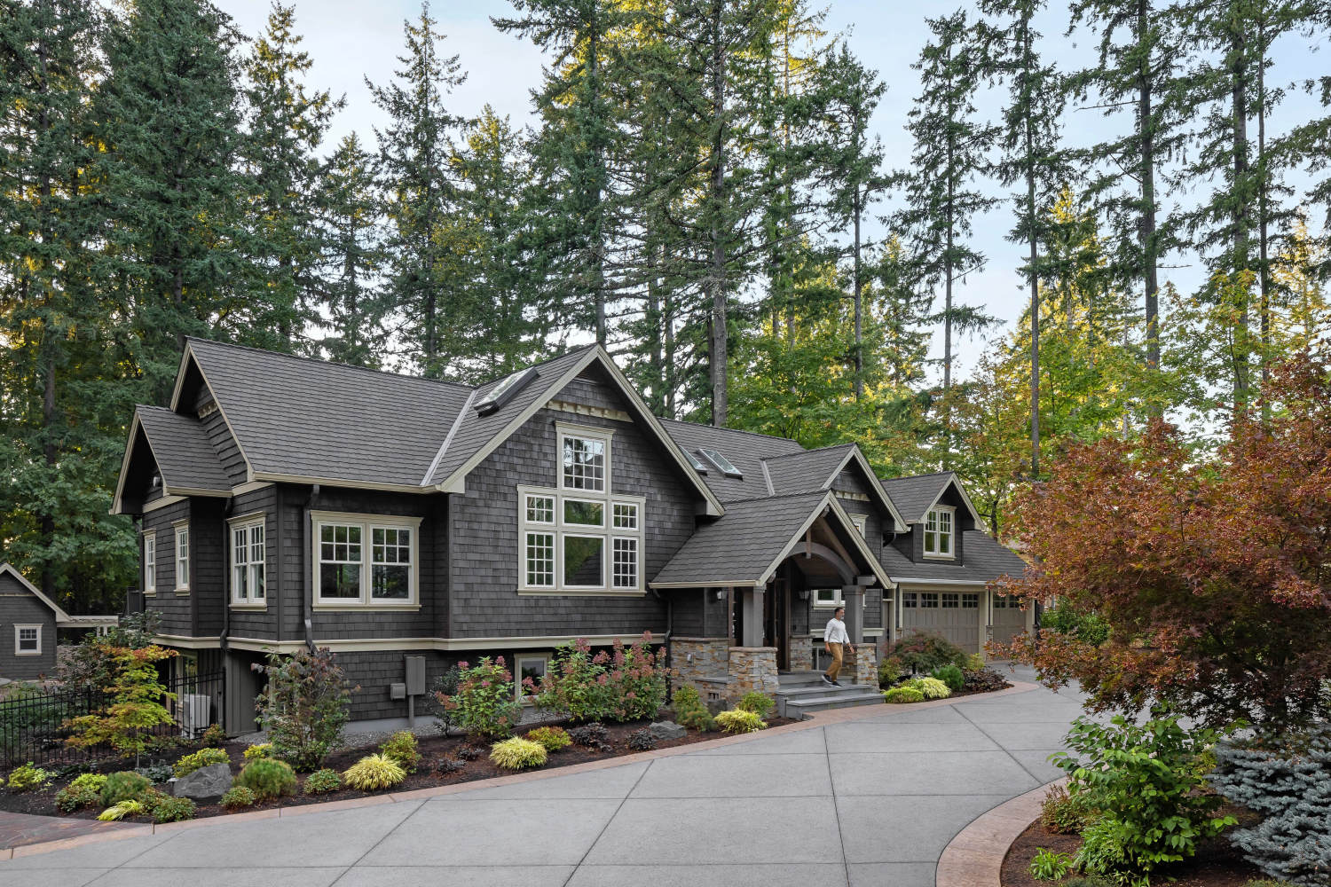 A large home featuring a driveway and trees, showcasing newly installed Renewal by Andersen composite windows in an exterior view