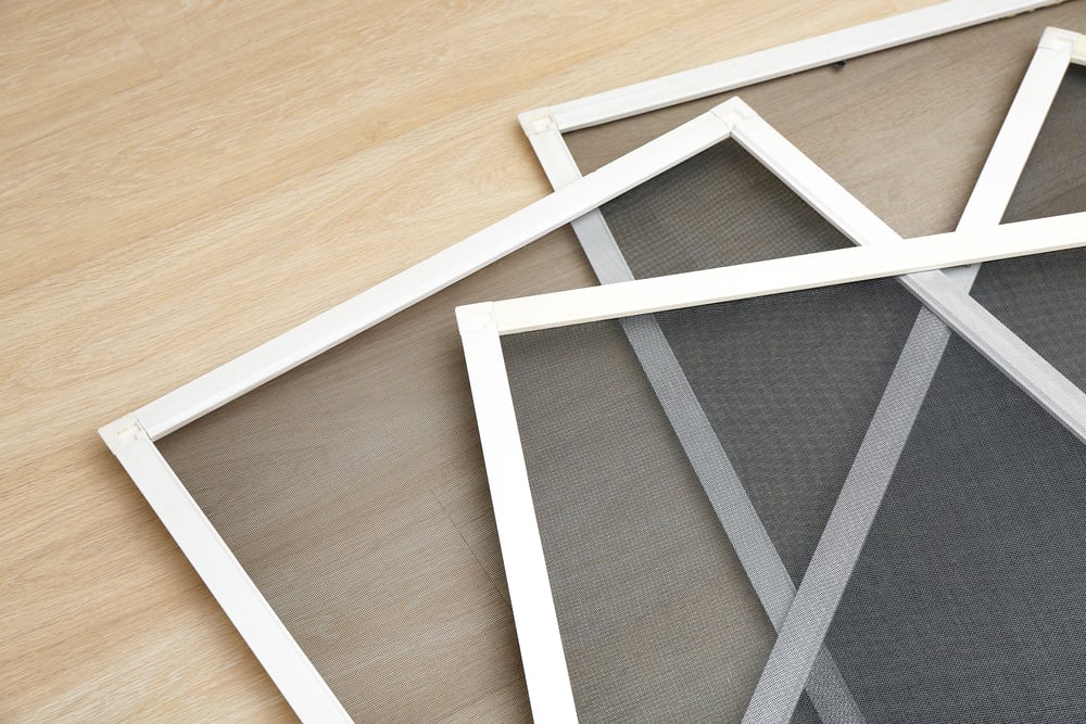 A 4 different insect screens arranged on top of each other laying on a wooden surface.