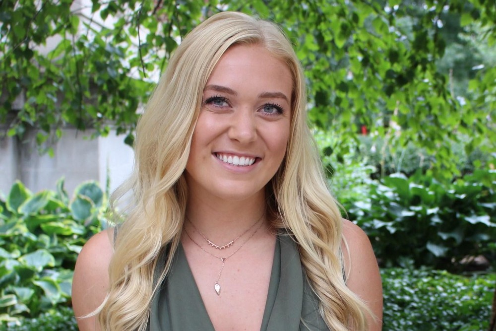 Internship spotlight claire stands in front of a floral background.