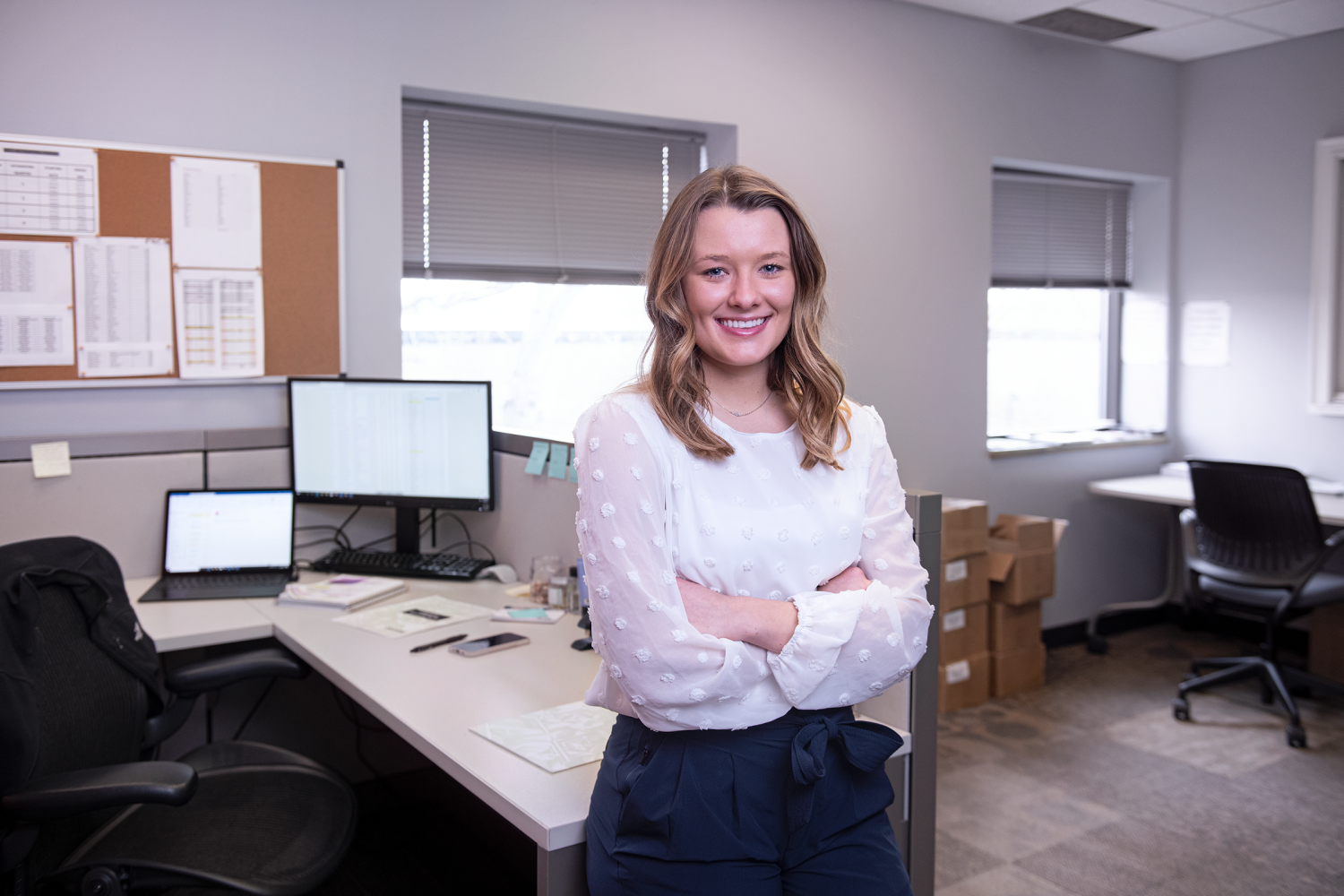 A Renewal by Andersen Adminstrative Assistant standing infront of her desk, her desk has a laptop attached to multiple screens