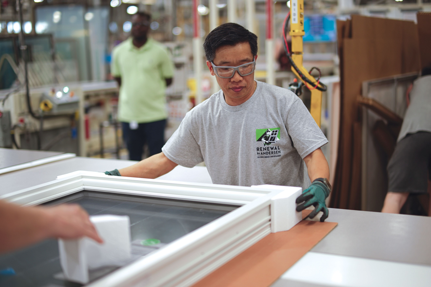 A Renewal by Andersen employee at inspecting a window at a manufacturing plant