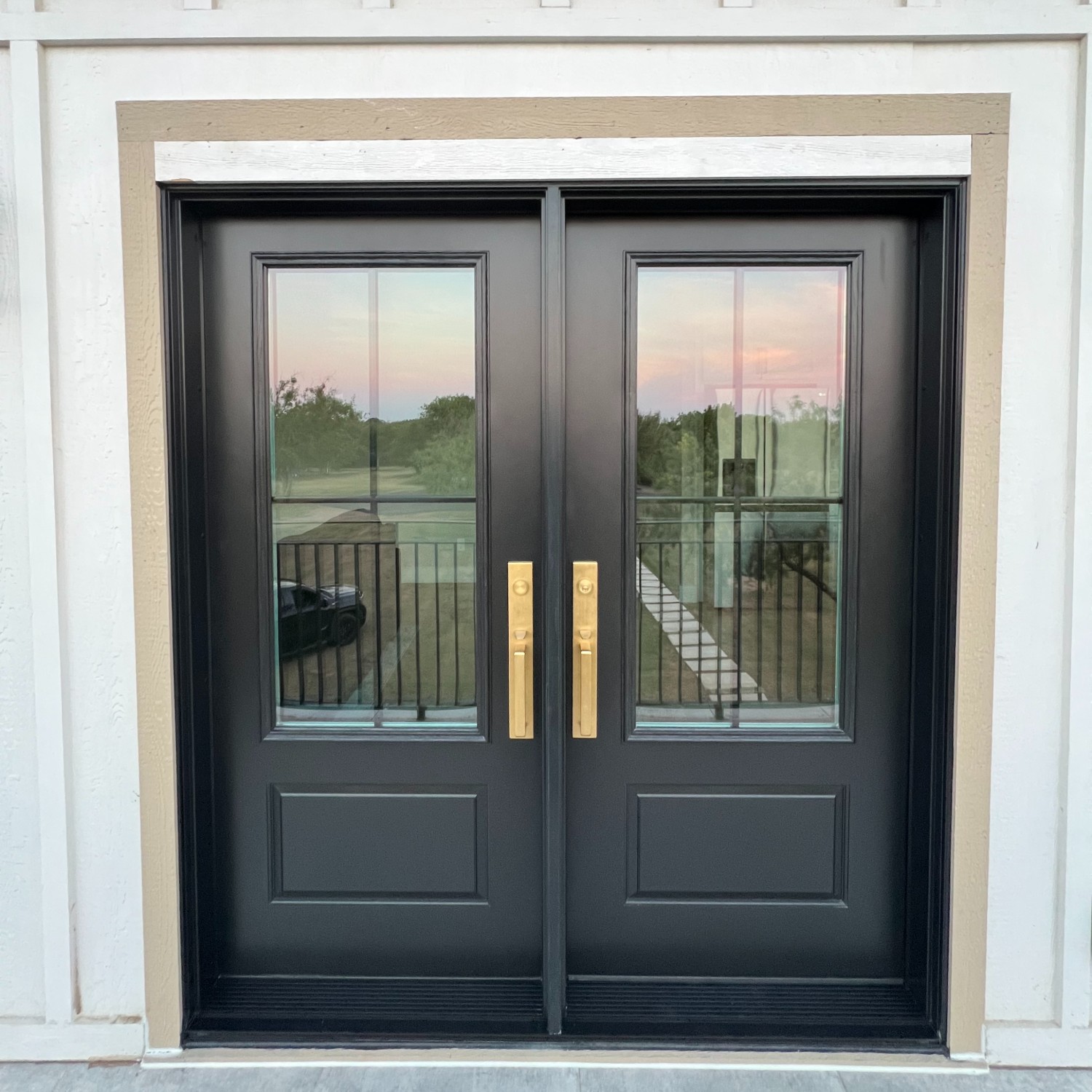 An ensemble entry double door in black with gold hardware.