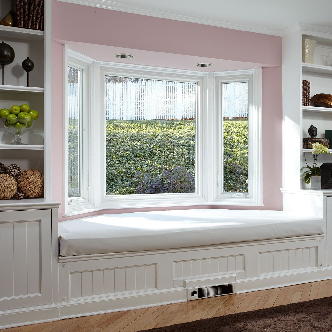 A salon or office room in a home. The room has pink walls and a white bay window.
