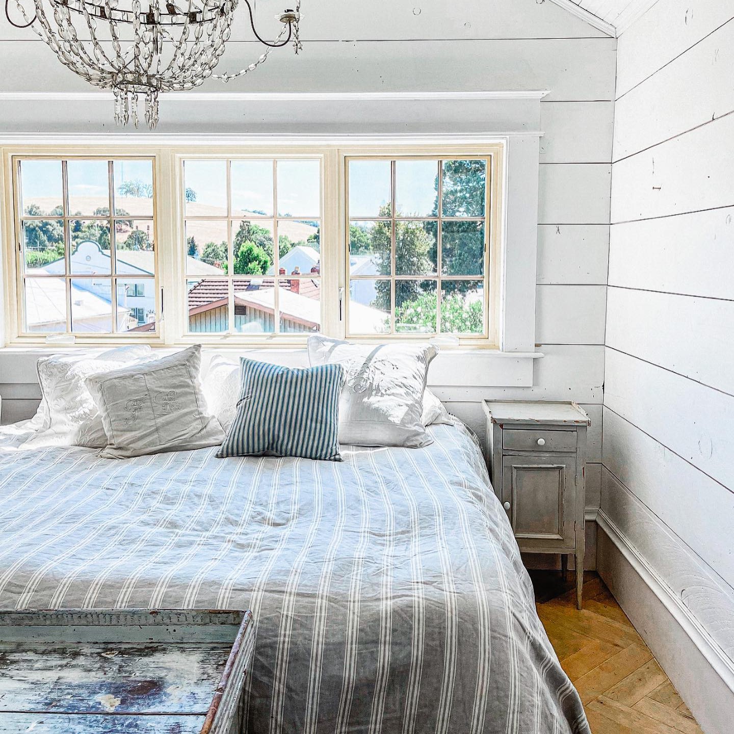 A farmhouse or shabby chic style bedroom with canvas colored casement windows.