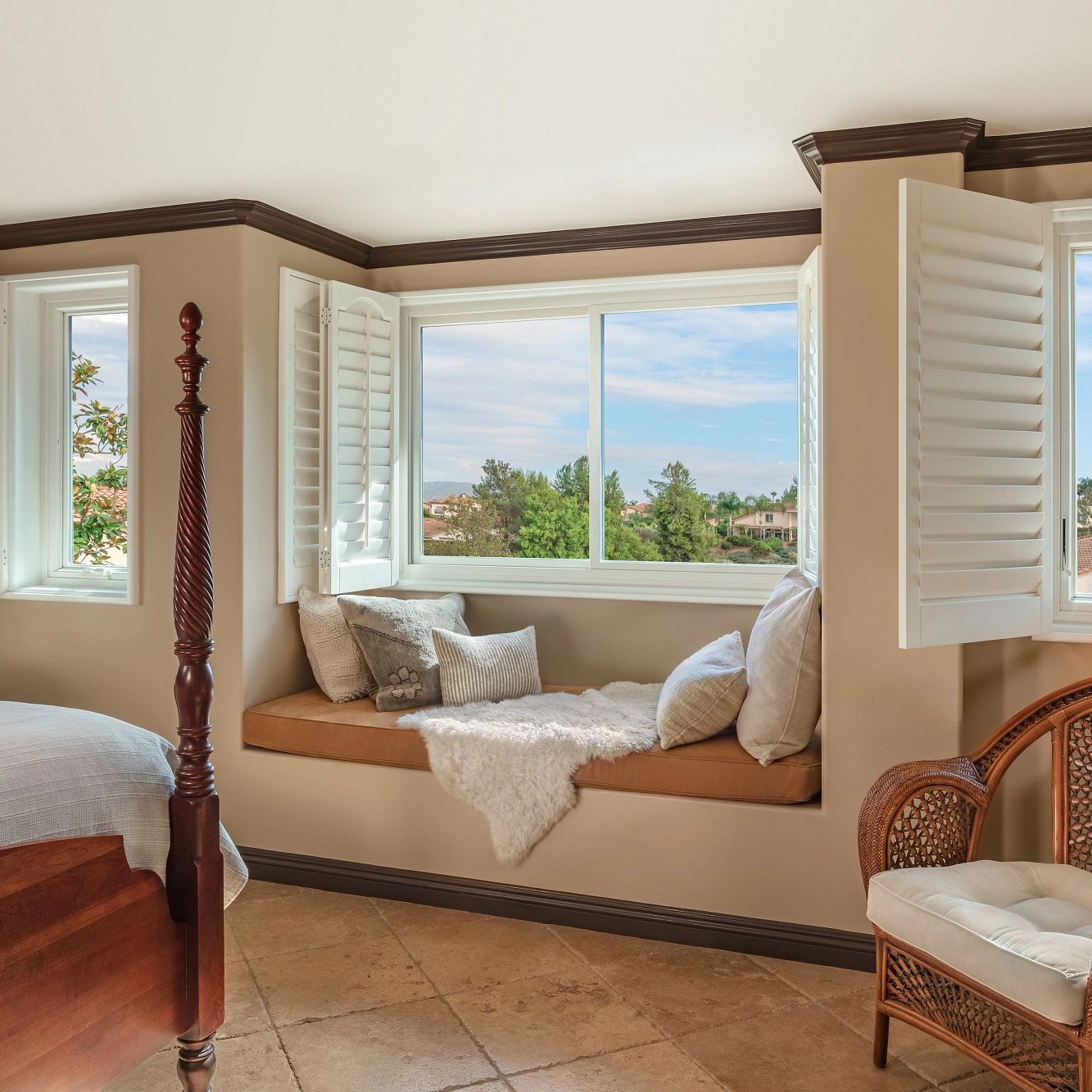 A bedroom with a gliding window. There is a bench seat below the white window.