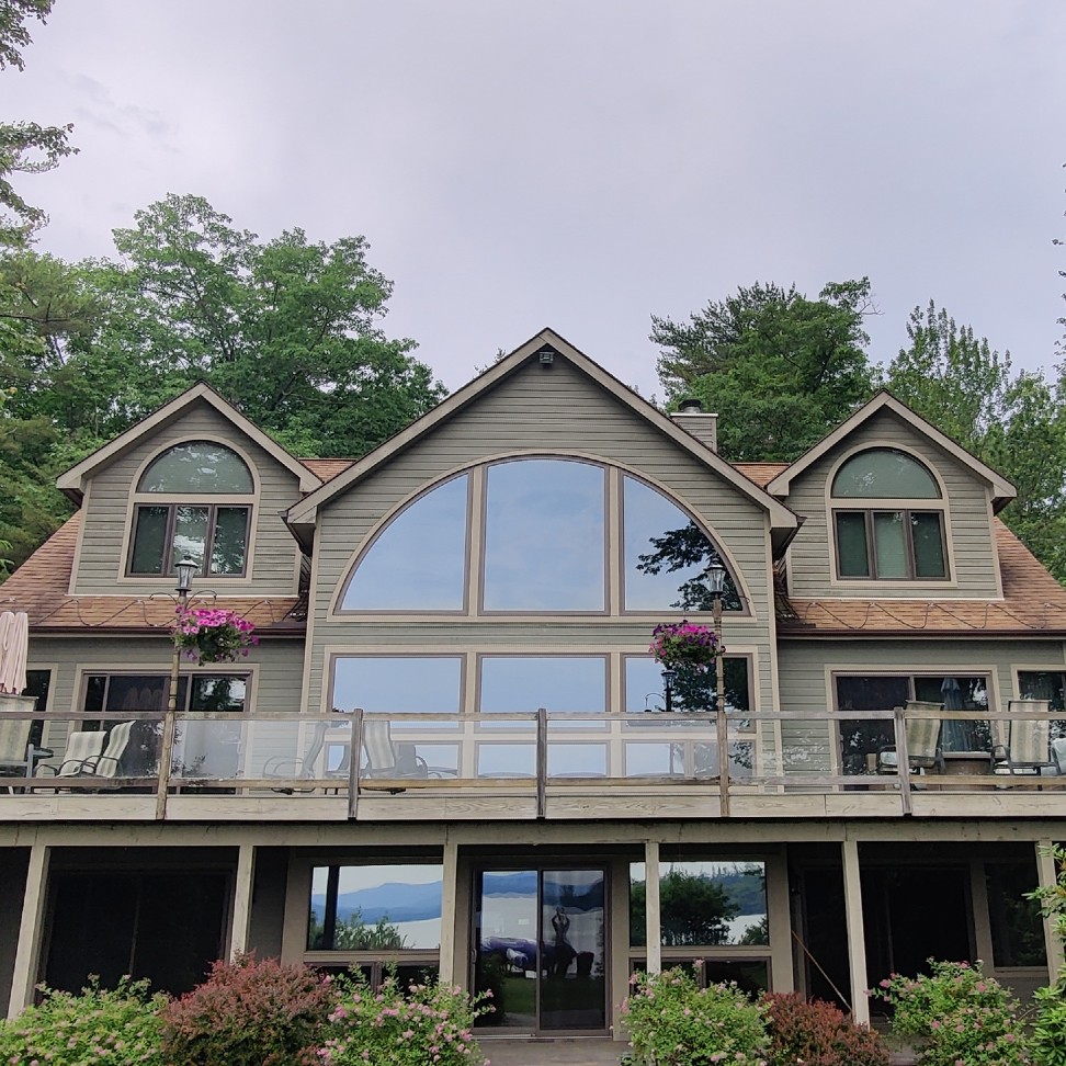 The exterior of a home, looking at the deck area. This has large specialty windows in the quarter circle shape.