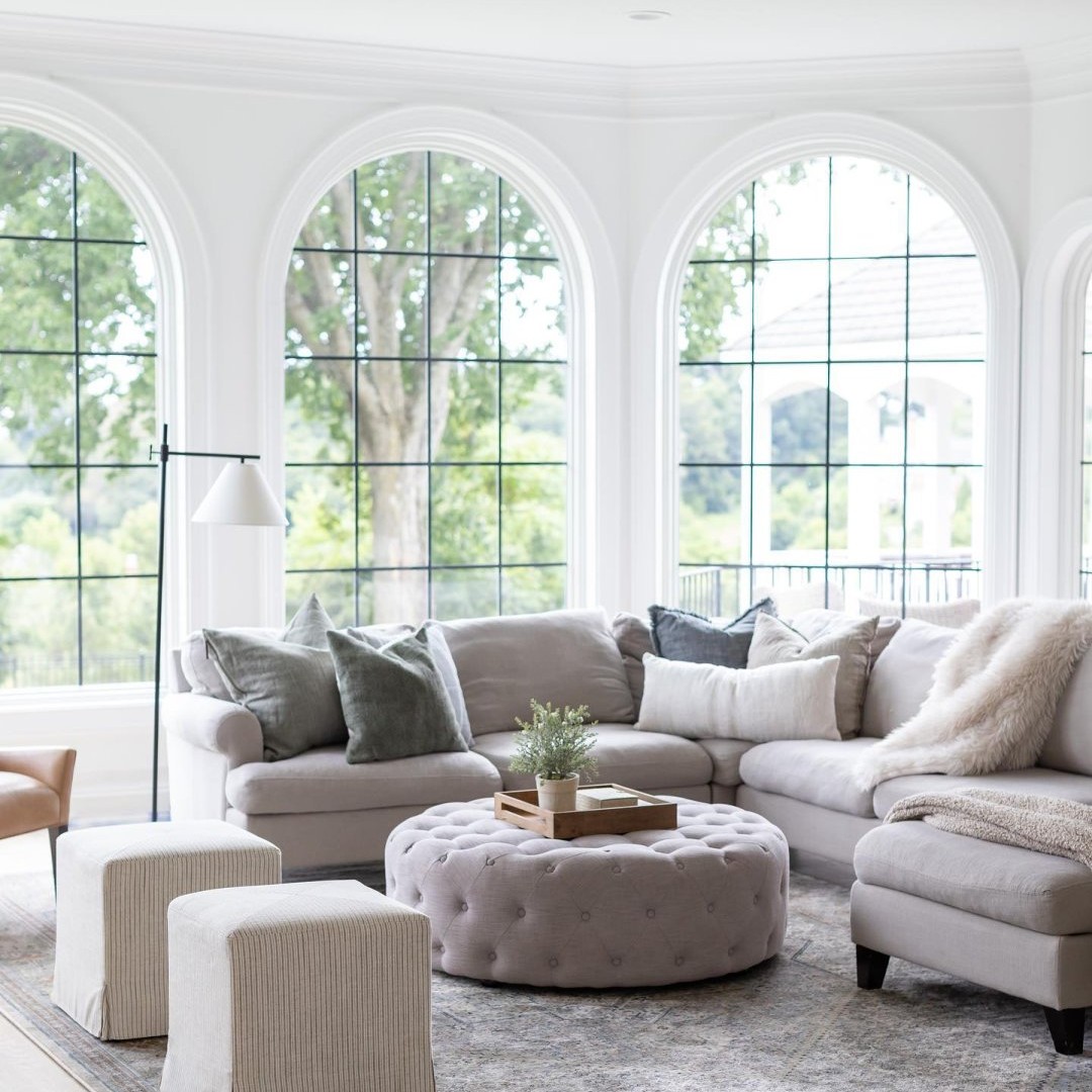 The living room in arched manor has springline windows. The room and window frames are white. The grilles are black.